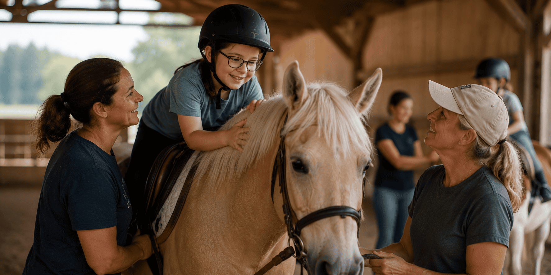 Child riding a therapy horse with two adults providing support in a warm indoor riding barn.